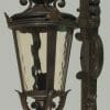 The Albany wall bracket is an antique-style lantern made of black metal, featuring glass panels and ornate scrollwork, mounted on a curved bracket.