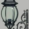 The Flinders wall bracket is a black metal outdoor lantern with clear glass panels and ornate scrollwork, shown mounted on a plain gray background.