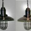 Two Lantern pendant lights with industrial metal shades and wire cages hang side by side against a plain wall.