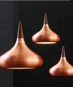 Three sleek Nona pendant lights, featuring copper finishes, hang gracefully against a dark background.