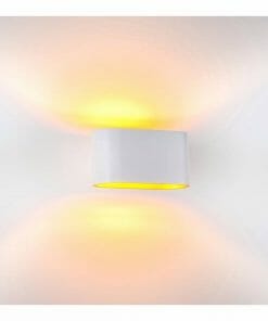 The HV8028 Wall light black features a white cylindrical design and emits warm yellow light both upward and downward, creating a soft glow on the white wall.