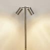 The Tivah HV1405-SS316 is a metal floor lamp with two cylindrical shades angled apart, casting light on a plain wall—ideal for achieving a Spike Spotlight effect in any modern space.