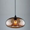 The Alana pendant showcases a round tinted glass shade with an exposed filament bulb, suspended from a black cord for an elegant look.