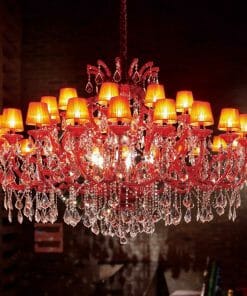 An Asfour crystal 6631-71" 42 light pendant with red crystal ornaments and multiple lit lampshades is suspended from the ceiling in a dimly lit room.