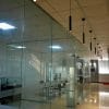 Modern office interior featuring the VIVA Pendant in Matt Black, with glass-walled conference rooms, ceiling lights, and a shiny tile floor. Empty chairs and desks are visible through the glass partitions.