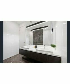 Modern bathroom with double sinks, large mirror, white countertops, and dark cabinetry illuminated by a Gamma 80W black or white LED. A soap dispenser and small potted plant are on the reflective surface.