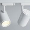 Two 12W LED track lights in Matt White are mounted on a ceiling rail; one fixture is turned on, while the other stays off.