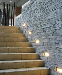 Brick exterior wall lights are embedded in a textured stone wall along the stone staircase, providing step illumination.