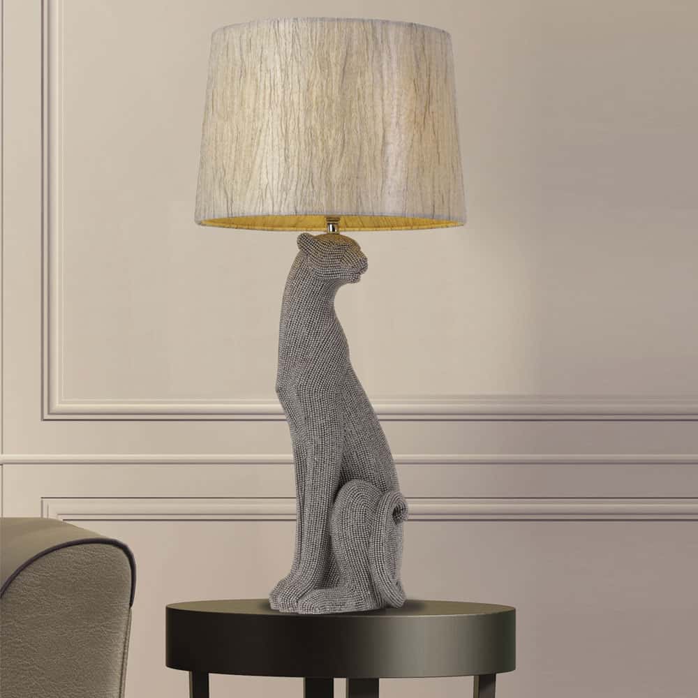 The Nala table lamp has a gray textured dog-shaped base and a round beige fabric shade, adding charm to any black circular side table.