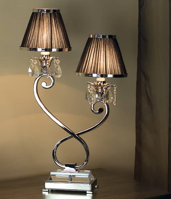 The Luxuria 2 light table lamp showcases two brown pleated shades, elegant curved arms, crystal accents, and a rectangular base for a refined touch on any wooden surface.