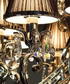 Close-up of the Luxuria 21 light crystal pendant, showcasing polished metal, sparkling crystal accents, and brown lampshades—all aglow with elegant illumination.