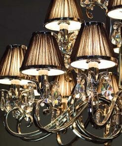 A close-up of the Luxuria 21 light crystal pendant featuring gold-colored arms, brown pleated lampshades, and sparkling illuminated crystal decorations.
