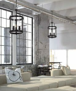 A modern industrial living space with large factory-style windows, exposed ductwork, beige furniture, a decorative bicycle pillow, and striking Newark 3 black pendant lights.