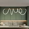 Modern kitchen with green cabinets, marble backsplash, and a large, abstract Swife Linear pendant hanging above the countertop with a bowl and bottles.