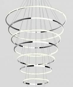 The Tuscan 8 ring Chrome chandelier showcases concentric illuminated rings in a spiral layout, suspended elegantly against a gray background.