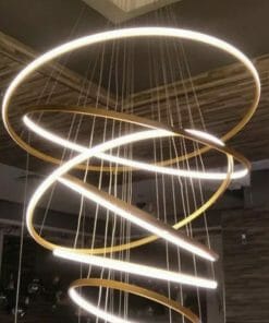 The Tuscan 8 ring Gold chandelier features spiral-shaped LED light rings, adding a modern touch to any contemporary interior as it hangs elegantly from the ceiling.