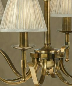Close-up of the Standford 3 Antique brass Shimmer shade chandelier with elegantly curved arms and pleated shades against a neutral background.