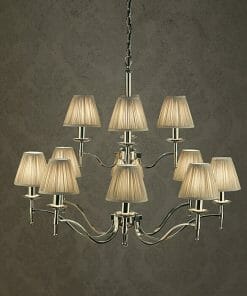 The Standford 12 Chrome Shimmer grey chandelier, featuring twelve arms and pleated beige shades, adds elegant sparkle against a textured grey wall.