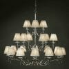 The Standford 21 Chrome Shimmer grey chandelier boasts a polished chrome frame, multiple cream lampshades, and subtle grey accents, creating elegant depth with its multi-tiered design.