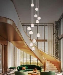 A modern lobby with a gold spiral staircase, green velvet seating, round coffee table, and Langton 15 cluster gold pendant lights, highlighted by floor-to-ceiling windows.