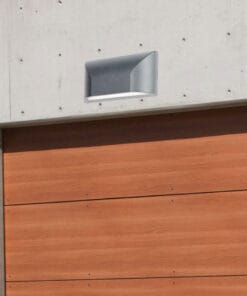 A Bloc Ext LED Wall Light is installed above a wooden garage door on a concrete wall.